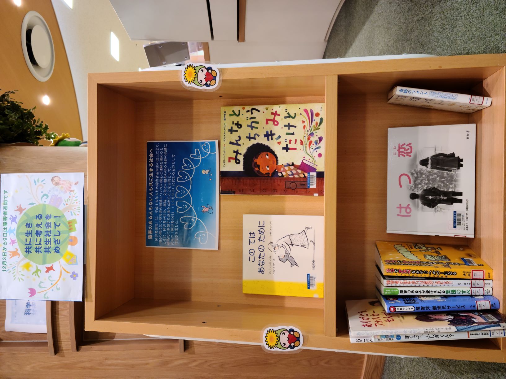 共に生き共に考える共生社会をめざして!とメッセージが掲載された、関連図書の本棚の写真です。