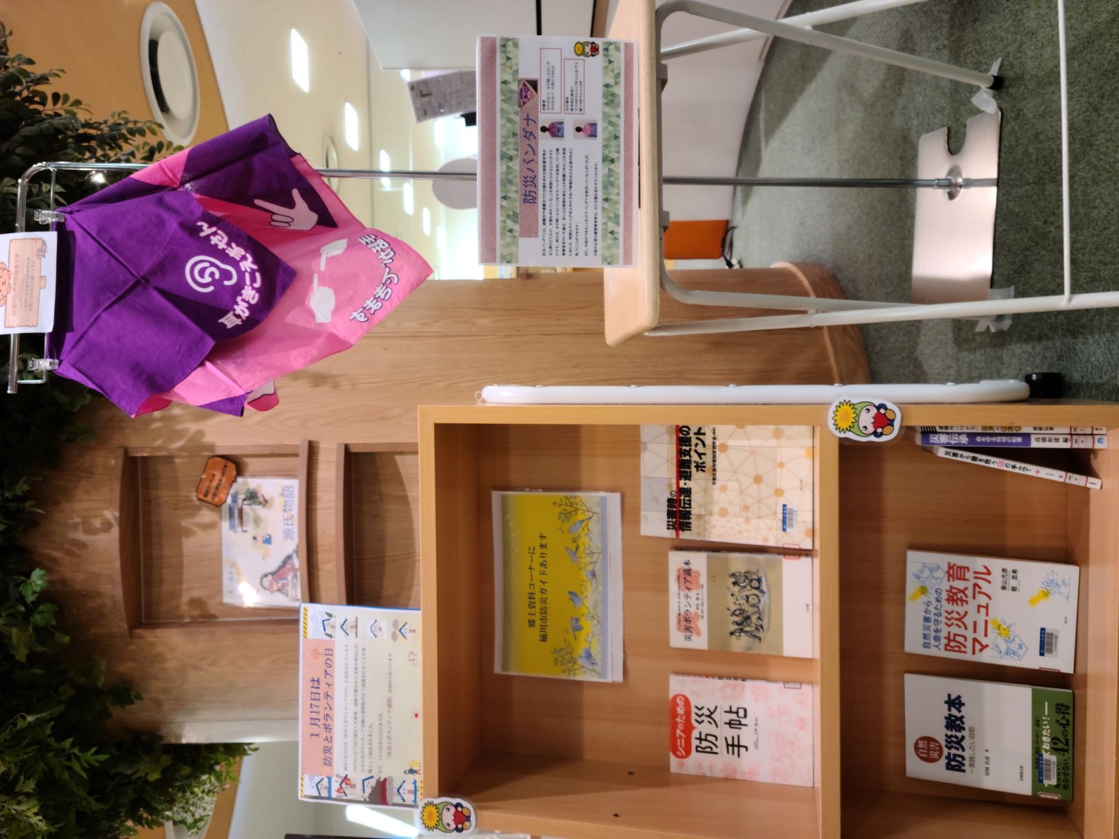 展示している棚の写真。防災とボランティア。防災バンダナの実物を吊り下げ展示。