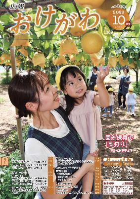桶川なのはな なかよし保育園の先生が園児を抱っこし、園児がなしに手を伸ばしている様子