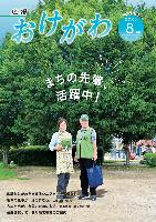 広報おけがわ8月号の表紙画像。広報紙配布員と市民が公園の木の前で広報をもって立っている写真
