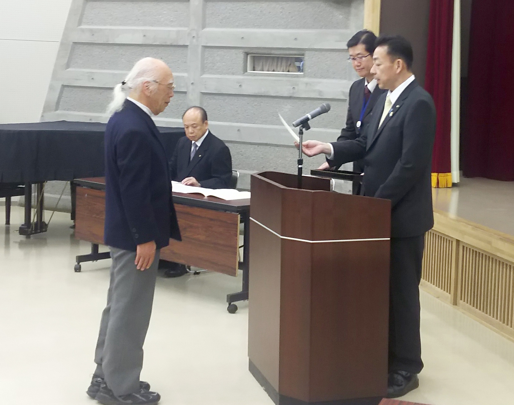 平成市民大学の卒業証書授与をするため、市長の前に向き合って卒業証書を受け取っている
