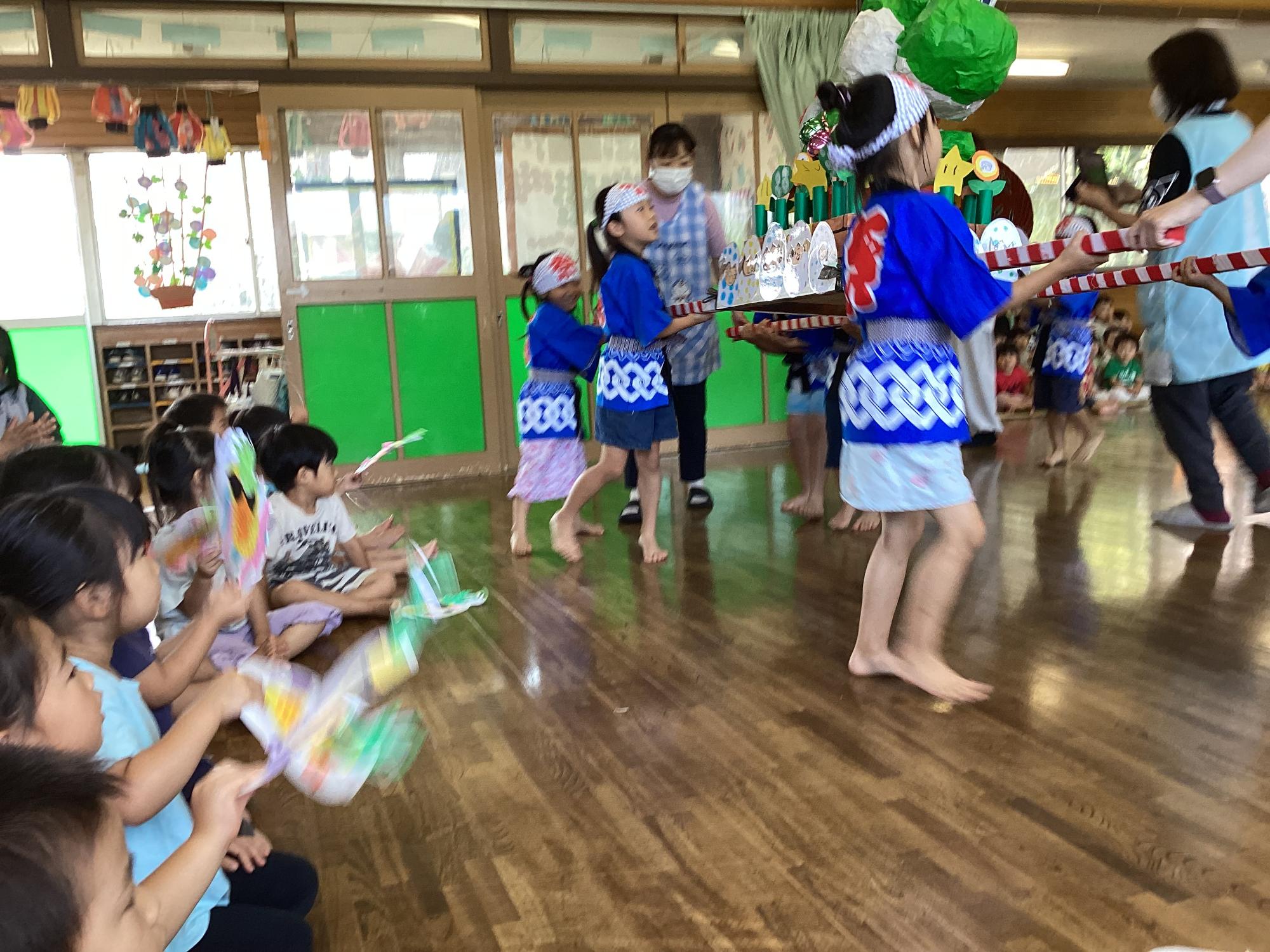 お神輿を担ぐ年長児と団扇で応援する3歳児
