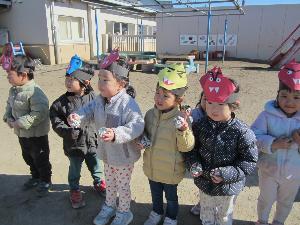 新聞紙を丸めた豆を両手に持ち投げる準備をする。