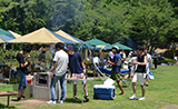 城山公園バーベキュー広場のページに飛ぶリンクバナー。バーベキューを楽しむ若者たちの様子が写っている。