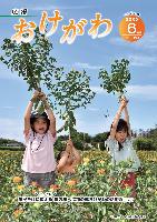 広報おけがわ6月号の表紙画像。晴れた空の下で、3人の子どもがべに花の中でべに花を持ち上げている写真