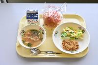 シーザーサラダ、冬瓜スープ、セレクトフライ、パン、牛乳、スプーン、ストローがおぼんにのっている写真。