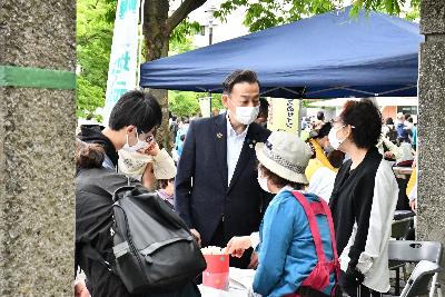 おけがわ春のふれあいフェスタの画像。出店団体の店前で団体の女性と言葉を交わすと小野桶川市長が写っている。