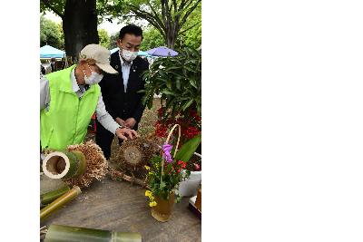 おけがわ春のふれあいフェスタの画像。桶川みどりの会の会員と小野桶川市長の2ショット。間伐された竹で作られた木工品の説明を受ける小野桶川市長が写っている。
