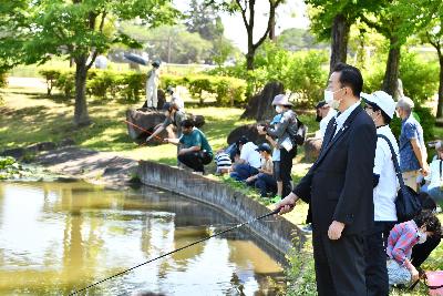 第4回初めての魚釣り体験の画像。城山公園の大池に釣り糸を垂らす小野桶川市長。水面のウキを見つめている。