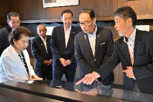 桶川市遺族連合会会長の臼田智子さんと館長から復原整備までの経緯などについて説明を受ける県知事、県議、桶川市長、議長の写真