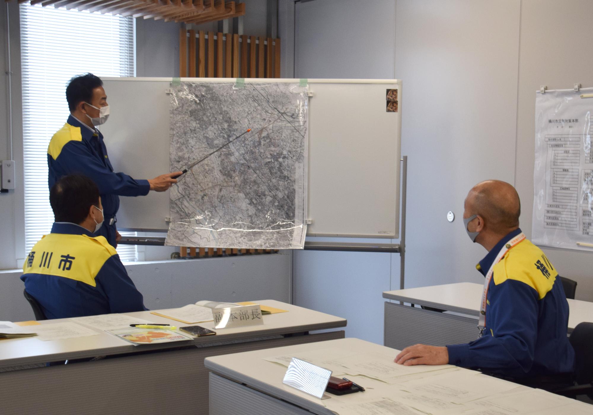 市役所会議室で行われた「図上検討型の災害対策本部訓練」で、小野市長がホワイトボードの前に立ち、説明をしている様子