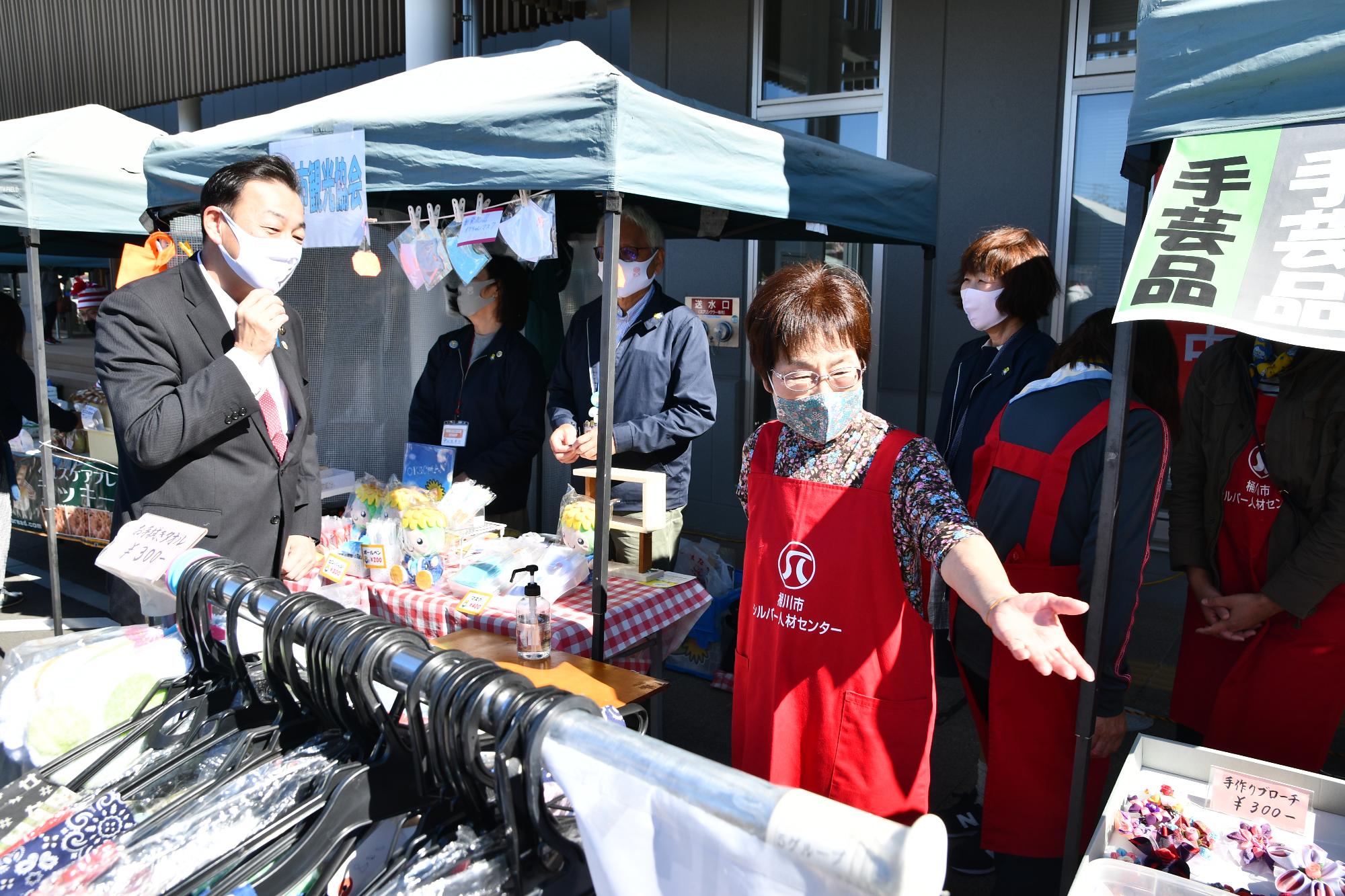 坂田コミュニティセンターで開催された「さかた”ぷち”マルシェ」で、出店の前でお店の人と市長が話している様子