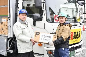 一般社団法人埼玉県トラック協会鴻巣支部の職員と小野市長が支援物資を持っている様子。