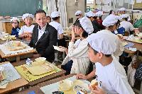 桶川市長と朝日小学校の生徒が給食を食べながら会話をしている写真