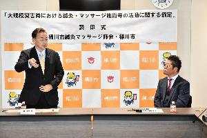 調印式で話をする桶川市長と桶川市鍼灸マッサージ師会の人