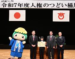 令和7年度人権の集い桶川の横断幕の前、オケちゃん、桶川市長、市内小学生、議長、教育長の4人の集合写真