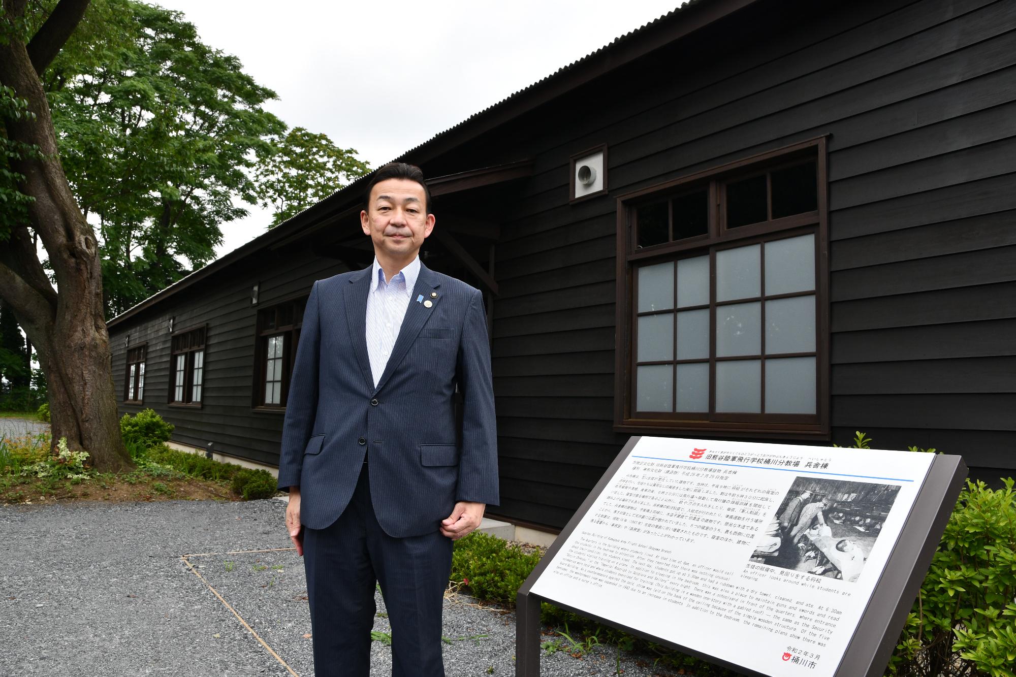桶川飛行学校平和祈念館の前に小野市長が立っている写真。