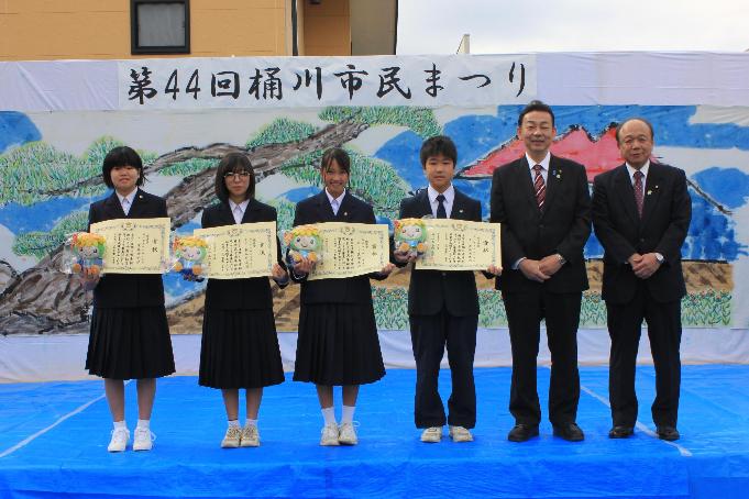 ロゴマーク表彰式写真、左から遠藤さん（桶川西中学校）、梶谷さん（桶川東中学校）、下里さん（桶川中学校）、渡邉さん（加納中学校）、小野市長、岩田教育長