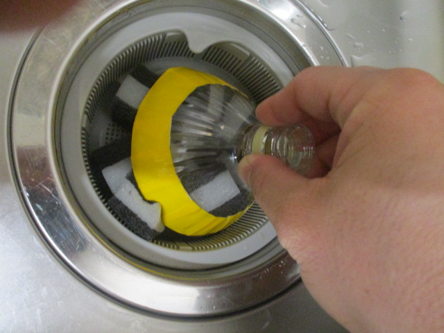 ペットボトルで作成した水切り器を使用して排水溝の水切りを行う様子